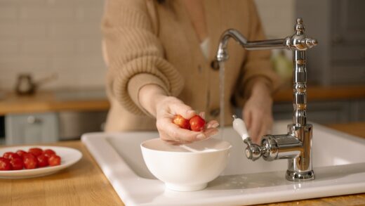 Kobieta myje warzywa przy zlewozmywaku w kuchni